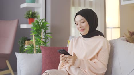 Woman-in-headscarf-is-texting-on-the-phone-and-smiling.